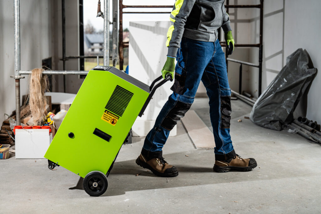 Majster jednoducho manipuluje s výkonným odvlhčovačom vzduchu STALCO PERFECT vďaka veľkým kolesám a pevnému madlu.